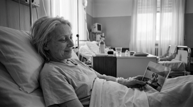 Hospital patient reclining in bed and holding a photograph